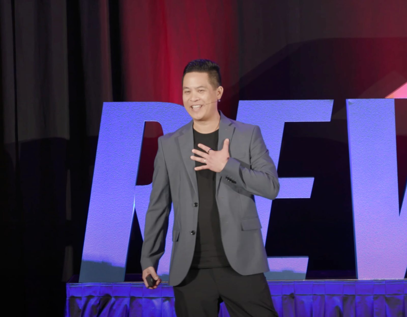 Michael Quan laughing on stage at RewbCon