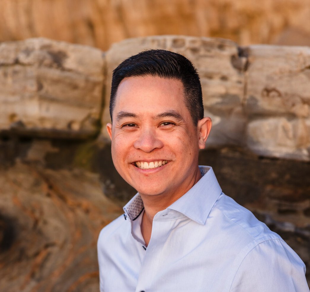 Michael Quan smiling in front of a sandstone wall